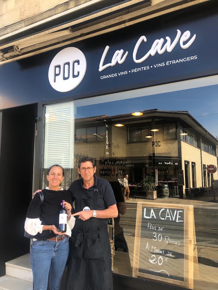 Robert et une cliente devant la cave, bouteille à la main